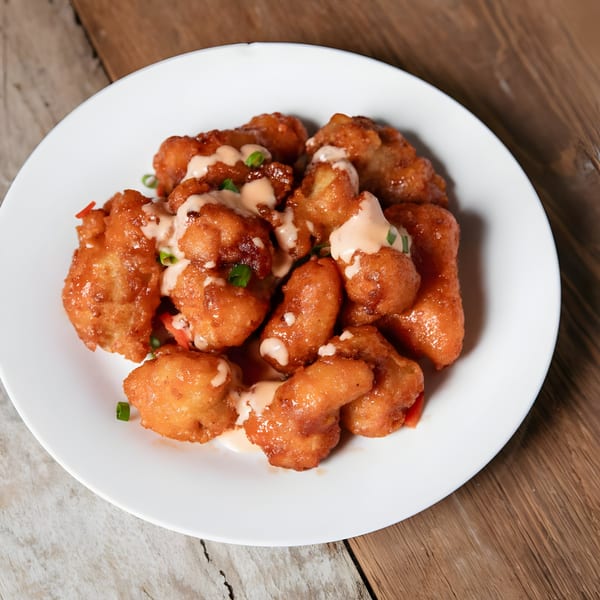 Crispy fried Caribbean fritters drizzled with a creamy sauce and garnished with green onions.