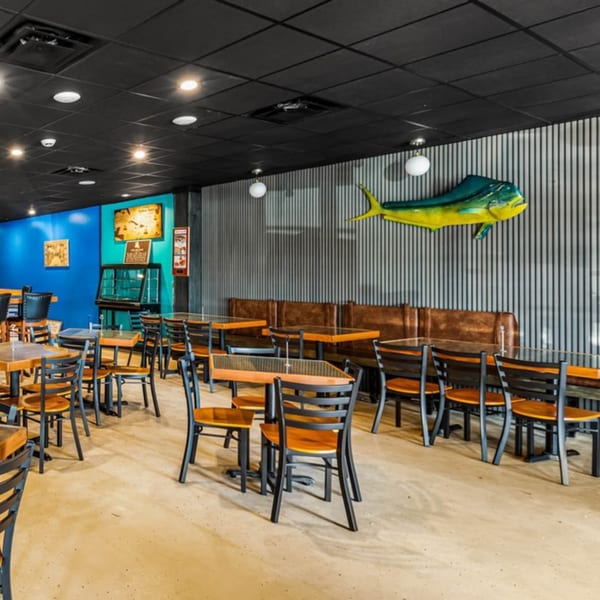 Bullfish Bistro dining room with tables, chairs, booths, and a large mahi-mahi sculpture on the wall.