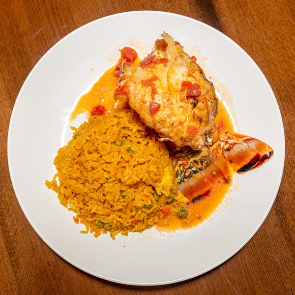 Bullfish Bistro's Caribbean lobster tail with tomato sauce and yellow rice on a white plate.