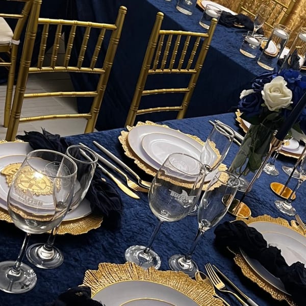 Elegant Bullfish Bistro table setting with navy blue tablecloth, gold chargers, white plates, and wine glasses.
